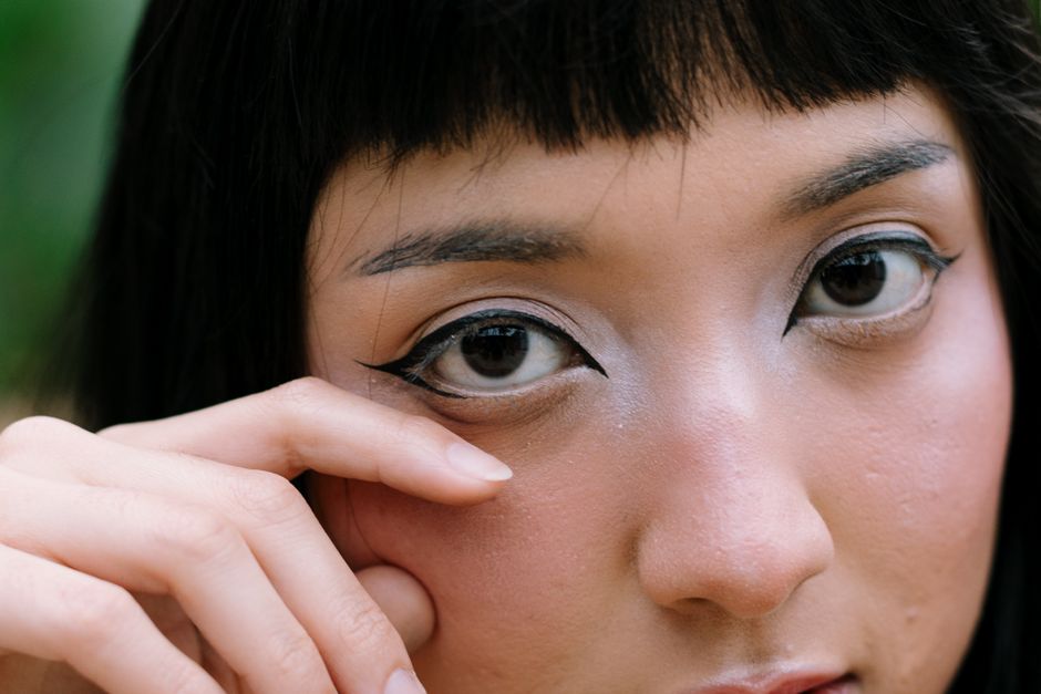 A detailed close-up of a woman's face highlighting bold makeup and intense eye expression.
