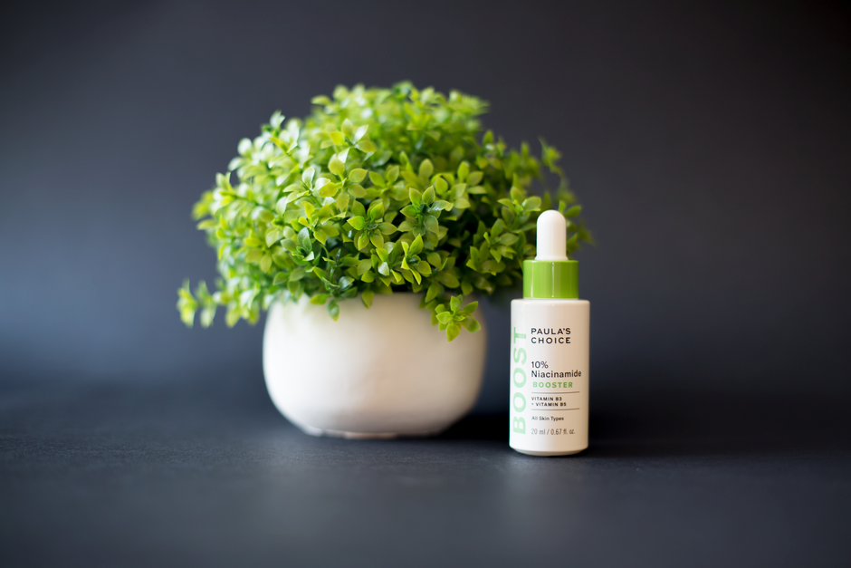 Close-up of a niacinamide serum dropper on a clean skincare flat lay
