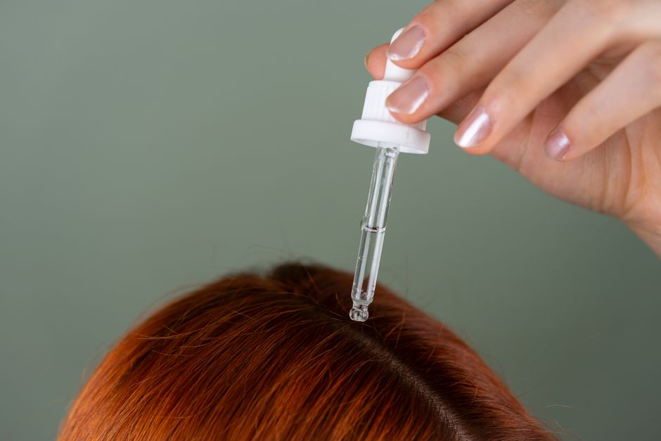woman applying hair serum treatment to scalp