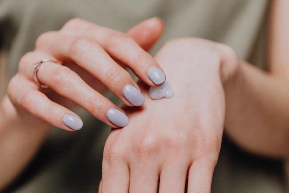 Close-up of hands applying moisturizer to face