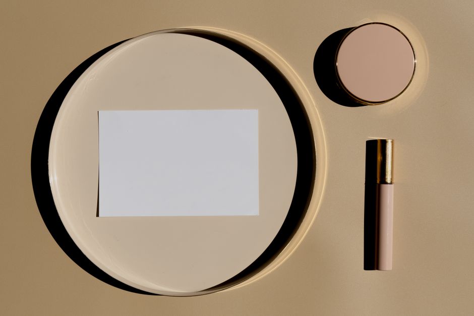 Flat lay of makeup essentials on a nude beige background, top view.