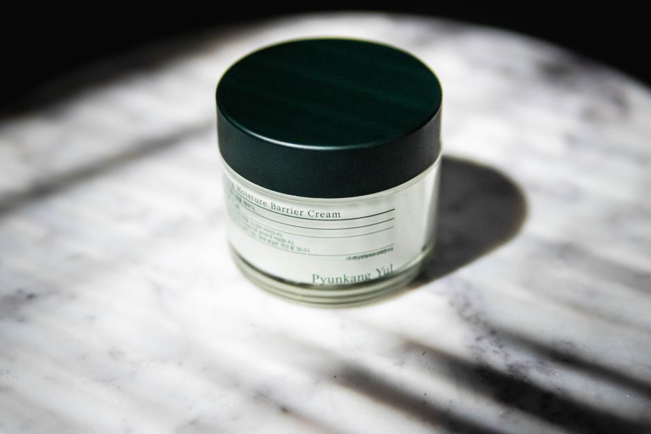 Close-up of a moisture barrier cream jar with stylish packaging on marble.