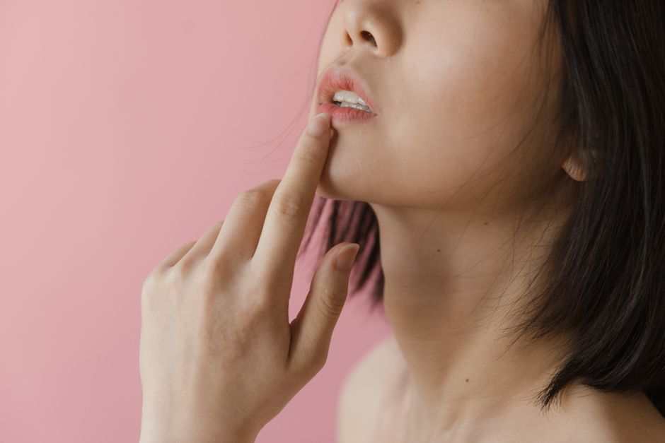 Close-up of a woman gently touching her jawline while examining her skin