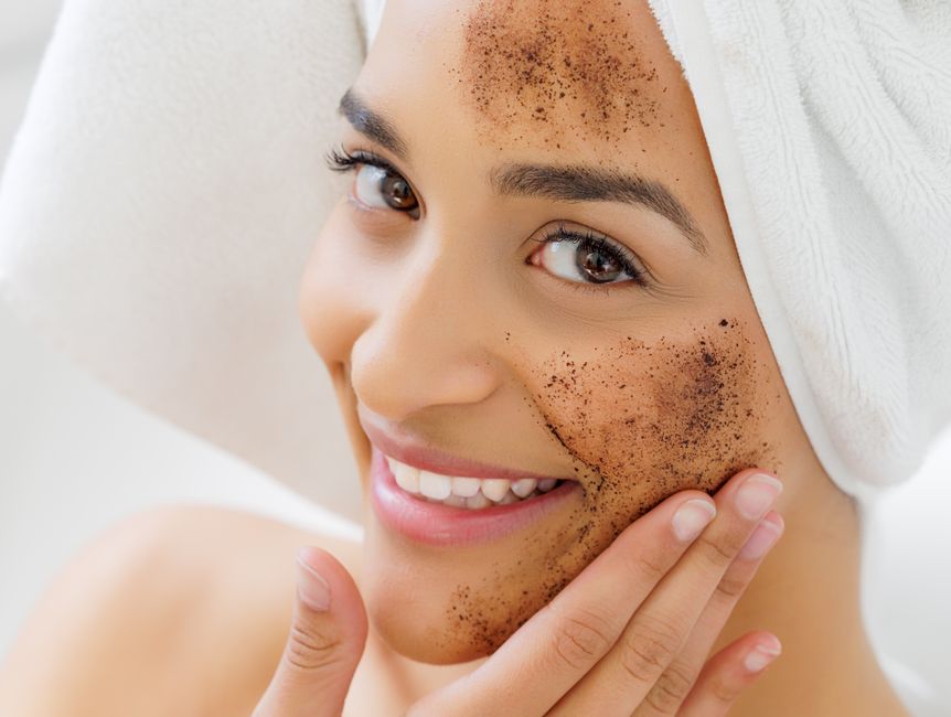 Close-up of a gentle exfoliating scrub on fingertips next to skincare bottles