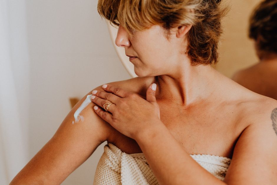 Person applying body acne treatment to their shoulder