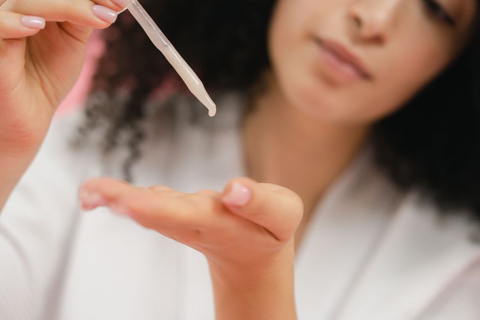 Woman applying a dropper of serum to her face
