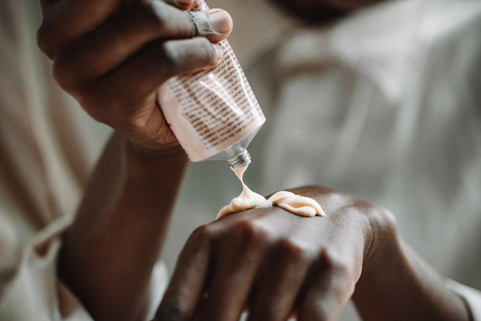 Skincare serum bottle held in dark-skinned hands