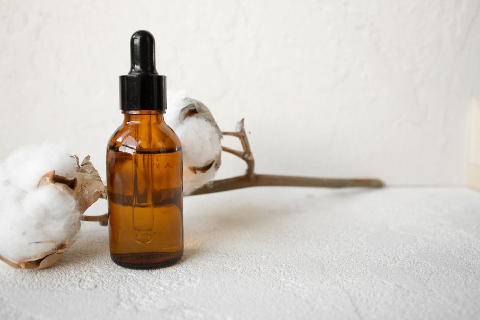 Amber dropper bottle of bakuchiol serum next to plant leaves on a light background