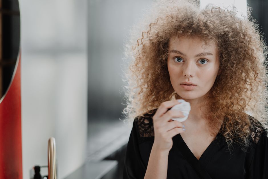 Woman applying a glycolic acid exfoliating toner with a cotton pad
