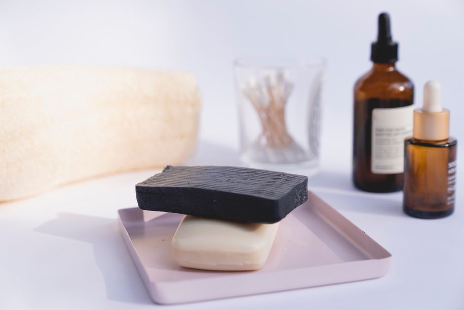 Bar of kojic acid soap and a dropper serum bottle on a bathroom counter
