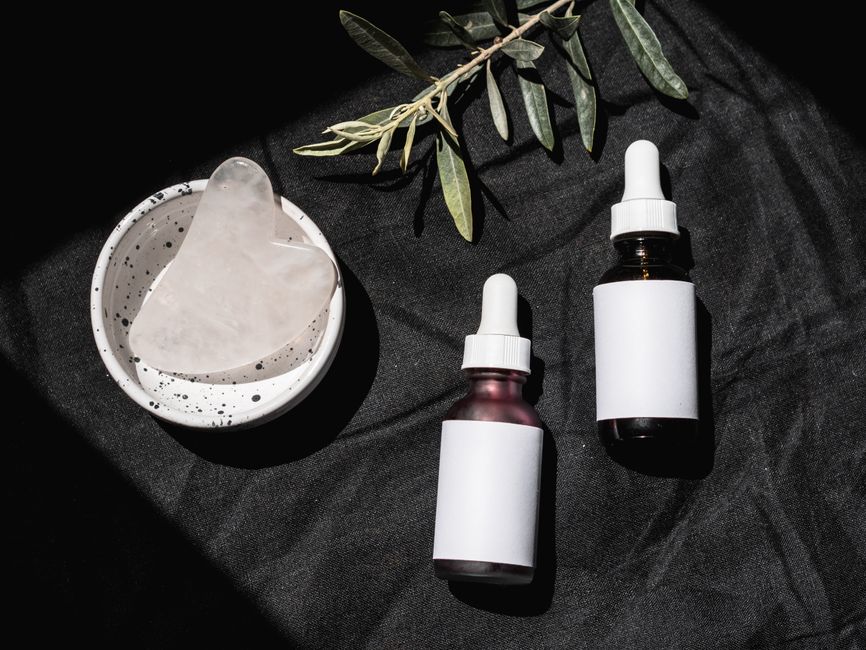 Flat lay of several skincare bottles and droppers on a marble surface